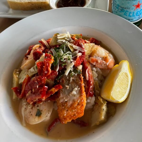 Babymoon Cafe's seafood risotto with salmon, shrimp, sun-dried tomatoes, and a lemon wedge.